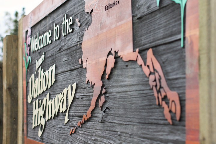 Wooden sign reading 'Welcome to the James Dalton Highway' with an Alaska map.